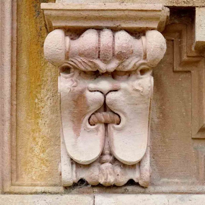 Ein grimmiges Löwengesicht mit gebundenem Maul an der Mauer der Certosa.