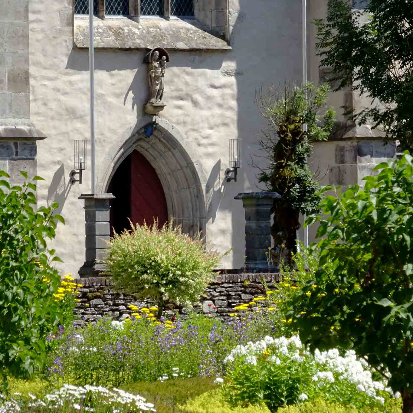 Maria mit dem Jesuskind schaut auf eine wunderschöne Gartenlandschaft.