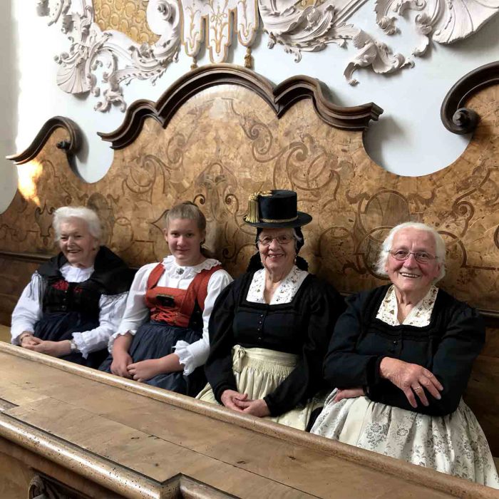 Die vier Damen haben in ihrer festlichen Sonntagstracht auf der Honoratiorinnenbank der Klosterkirche Stams Platz genommen.