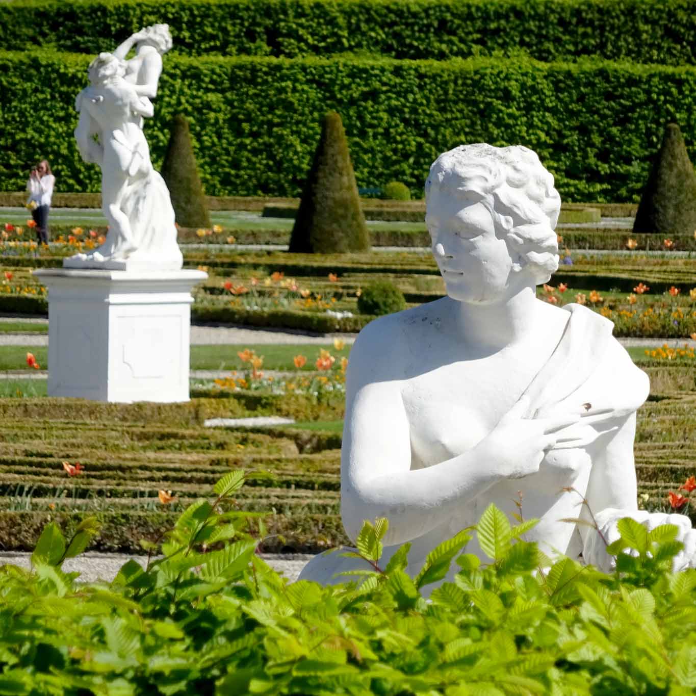 Göttin Aurora nestelt verzückt an ihrem Kleid in Betrachtung des Treibens im Garten.