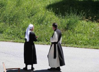Nonne der Barherzigen Schwestern mit Zisterzienser-Mönch im Gespräch.