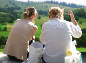 Zwei Frauen sitzend vor einer Landschaft der rumänischen Nordkarpaten.