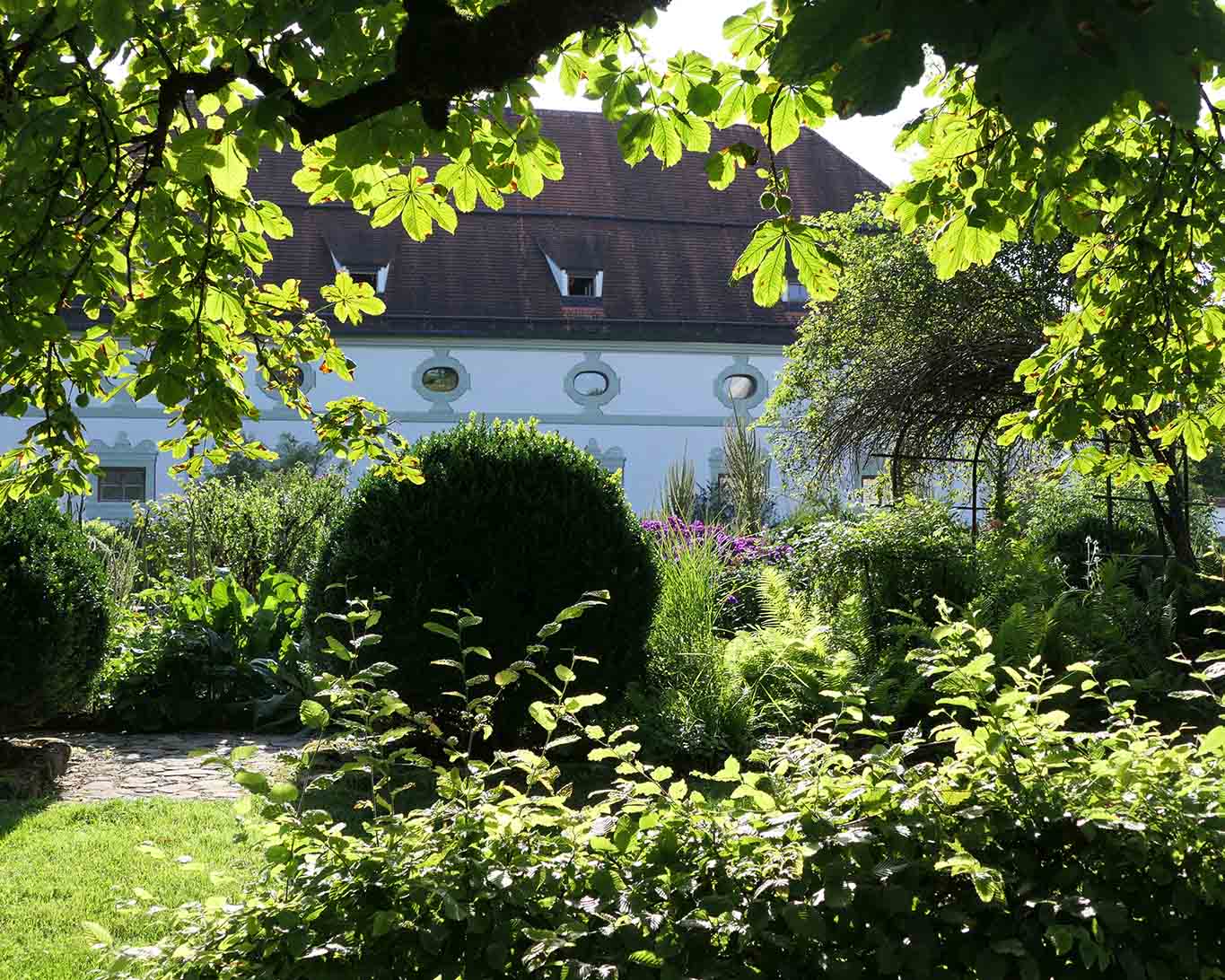 Blick durch die äume auf den Meditationsgarten des Klosters Benediktbeuern.