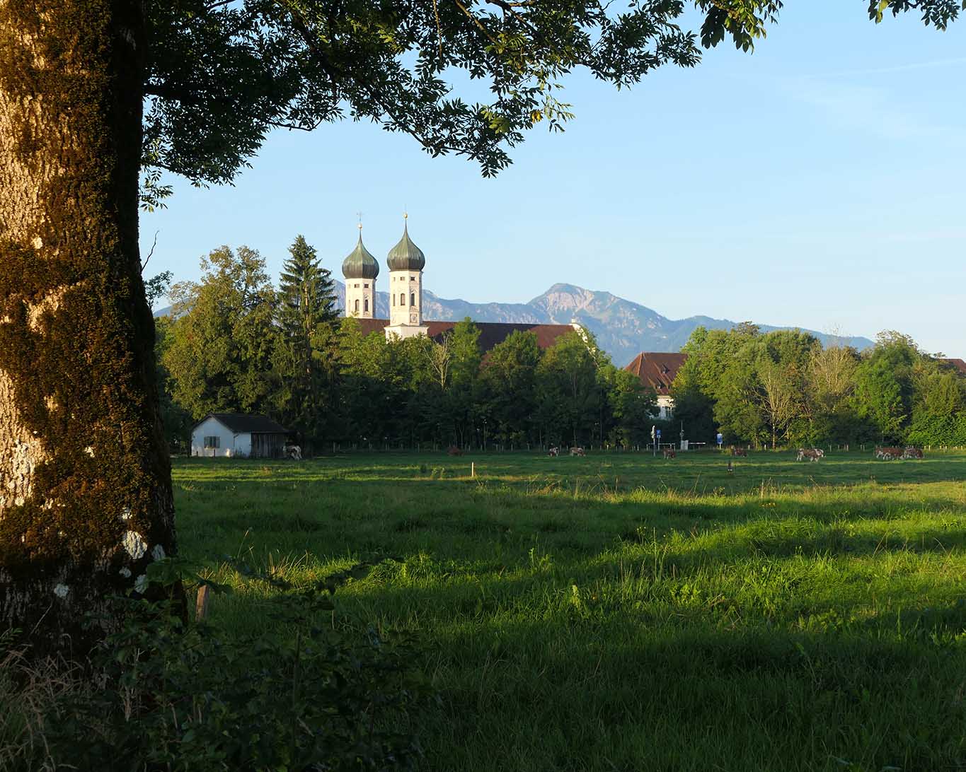 Das Kloster Benediktbeuern im ersten Morgenlicht mit den Alpen im Hintergrund.