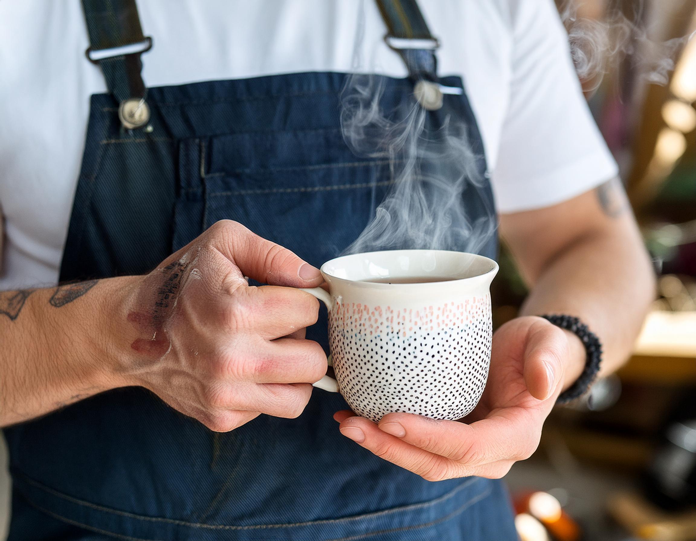 Teepause für Handwerker in Latzhose und weissem T-Shirt in einem entspannten Moment.