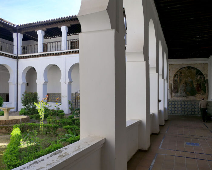 Blick in den Claustro de los Laureles mit seinen doppelstöckigen Arkaden und dem Sockel mit den bunten Talavera-Fliesen aus dem 16. Jahrhundert.