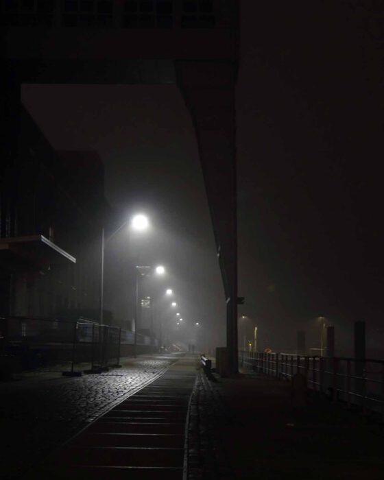 Kranhäuser nachts im kalten Winternebel der Elbe mit Laternen spärlich beleuchtet.